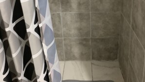 Ein Badezimmer mit Duschbereich, gefliesten Wänden und einer Duschmatte.