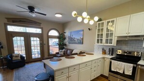 A modern kitchen with white cabinets, a black stove, and a dining area with a brown leather couch. - The Top Shelf on the Bourbon Trail in Historical Downtown Versailles (Versailles)
