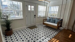 A hallway with a star-patterned floor, a wooden bench with cushions, and a hanging light fixture. - The Breaker-2 Blks from Beach (Virginia Beach)