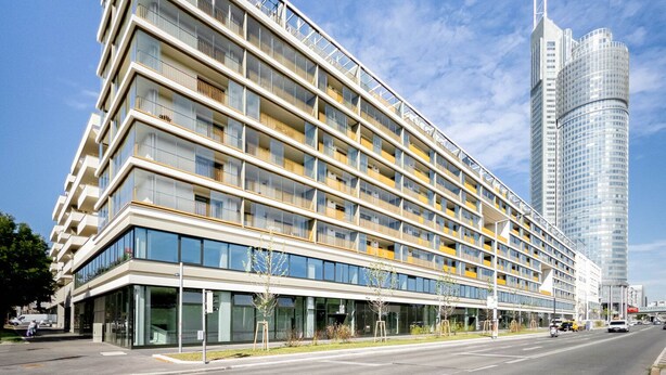 Un hôtel moderne à plusieurs étages, doté d’une façade en verre, de nombreux balcons et d’un imposant gratte-ciel adjacent.