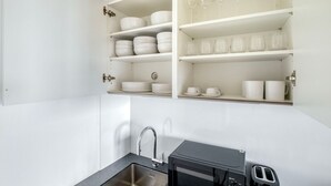 Une cuisine avec des armoires blanches, un évier en acier inoxydable et un four à micro-ondes.