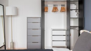Une chambre à coucher moderne avec une armoire grise, une table de chevet et une lampe.