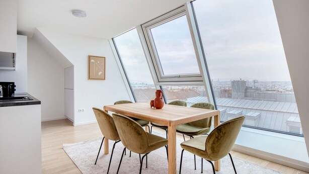 Une cuisine moderne avec un coin repas, de grandes fenêtres et une vue sur la ville.