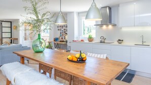 A modern kitchen with white cabinets, a wooden dining table with a fruit bowl, and pendant lights. - CASA GEMA - Fabulous holiday home with saltwater pool and free WiFi (Selva)