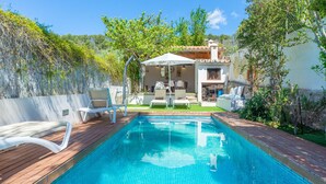 A swimming pool with a wooden deck, surrounded by a garden and a white building with a tiled roof. - CASA GEMA - Fabulous holiday home with saltwater pool and free WiFi (Selva)