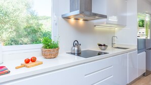 A modern kitchen with white cabinetry, a stainless steel kettle, a sink, and a window with a view of greenery. - CASA GEMA - Fabulous holiday home with saltwater pool and free WiFi (Selva)