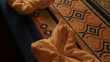 Un letto con una coperta fantasia e due asciugamani piegati sopra.