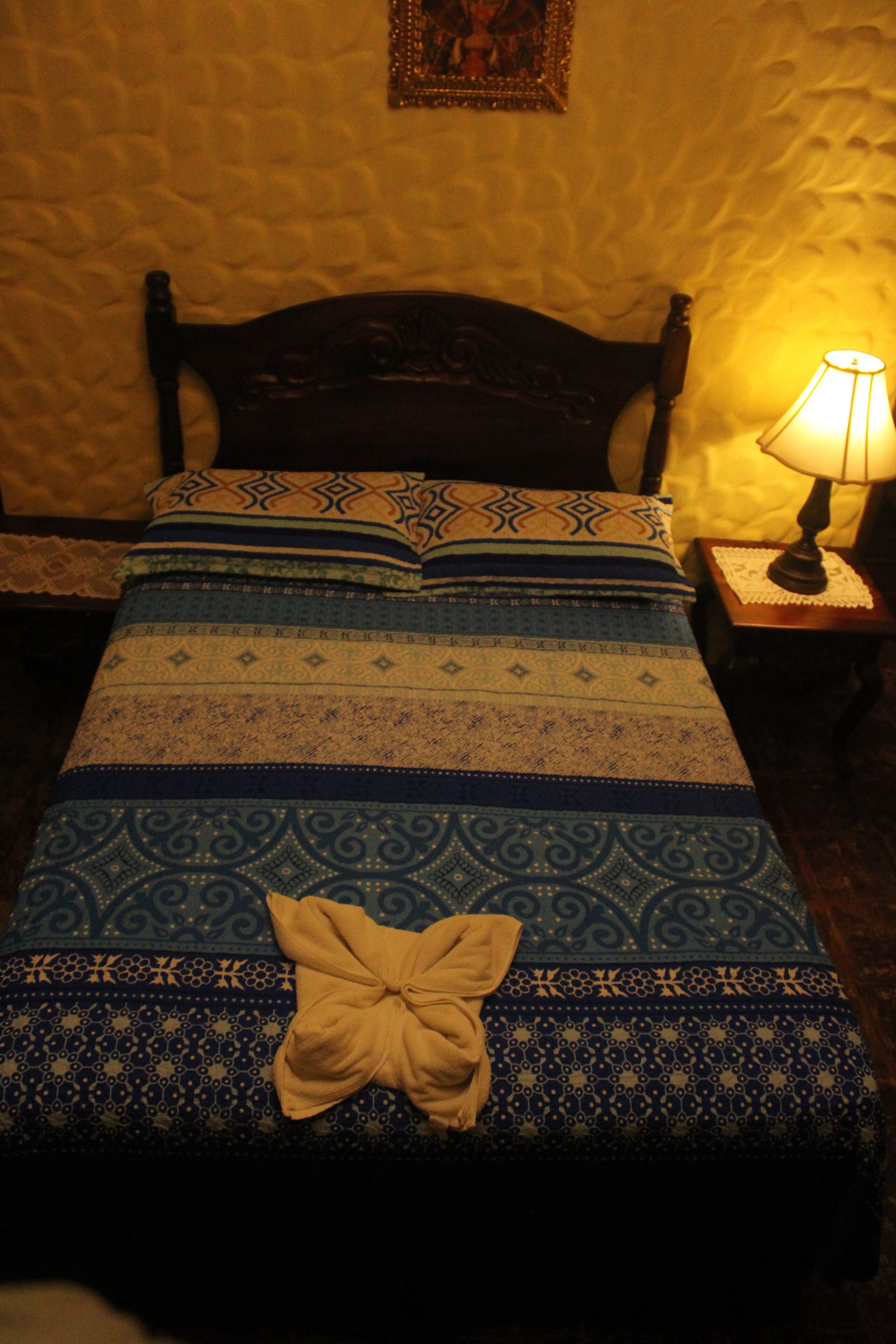 Una cama con ropa de cama estampada y una almohada decorativa.