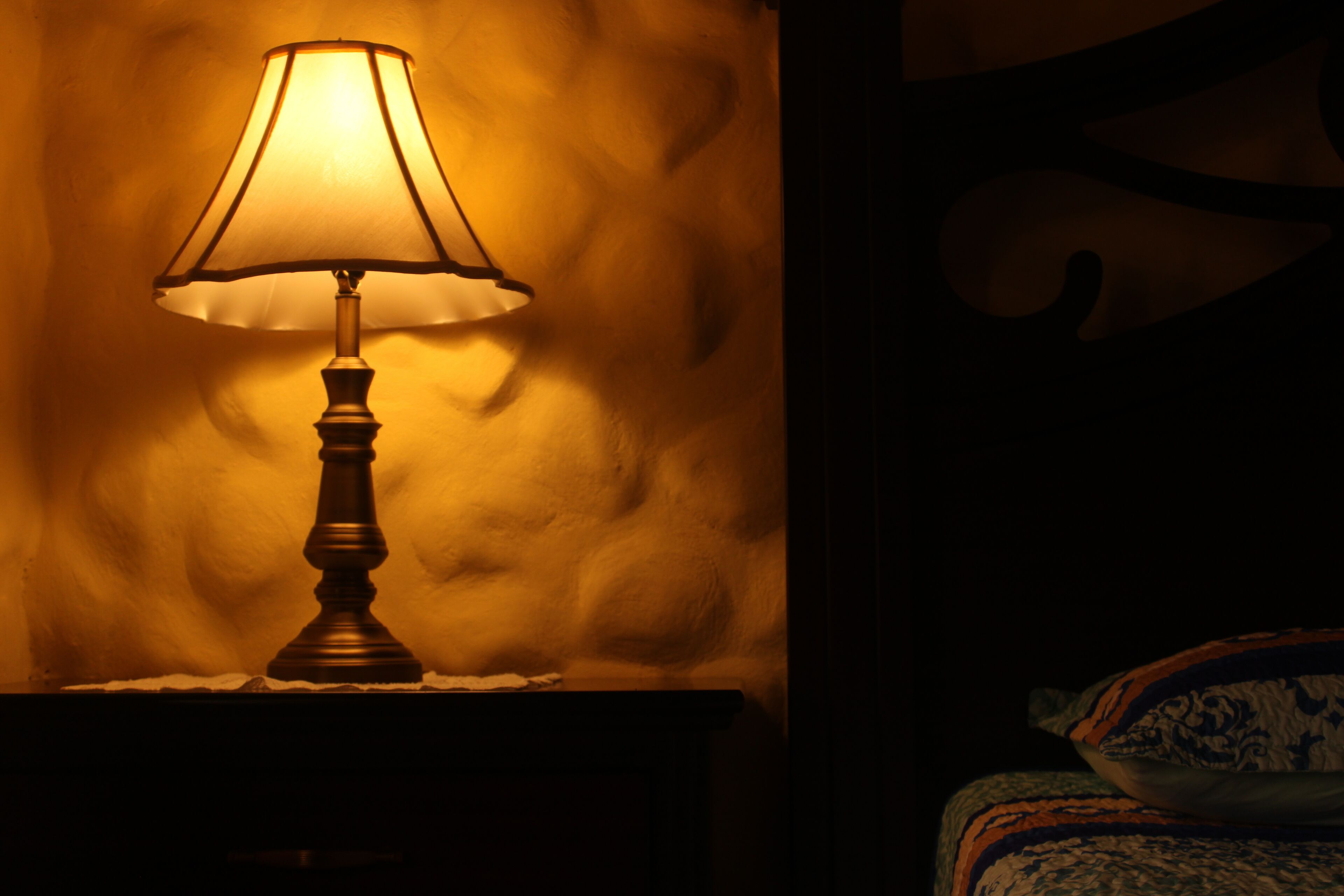 Une lampe sur une table de chevet, avec un mur à motifs en arrière-plan.