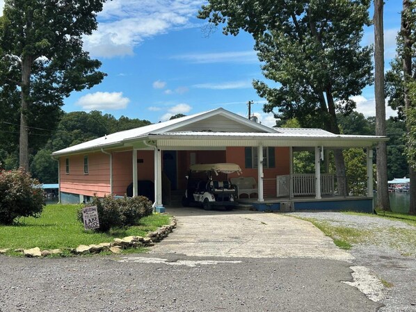 Una casa con porche, un espacio cubierto y un carrito de golf.