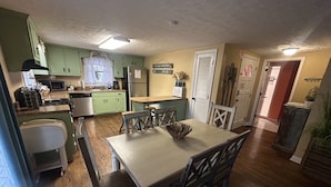 A kitchen with green cabinets, a dining table with chairs, and a refrigerator. - Beautiful Lake Front Home overlooking Lake Douglas with Hot Tub and Golf Cart! (Dandridge)