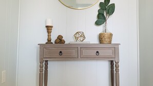 Une console en bois dotée de deux tiroirs, d’un miroir rond et d’une plante en pot.