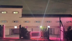 A motel with a sign, a gated entrance, and a parking lot at night. - HERA DRIVE IN HOTEL (Jeju City)