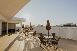Eine Dachterrasse mit Sitzgelegenheiten und Sonnenschirmen mit Blick auf eine Stadtlandschaft.