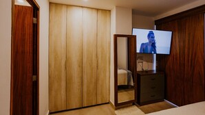 Ein Schlafzimmer mit einem Holfischschrank, einem Fernseher auf einem Schrank und einem Spiegel.