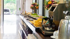 A buffet line with various food items, a coffee machine, and decorative flowers. - Con Son Blue Sea (Ho Chi Minh City)