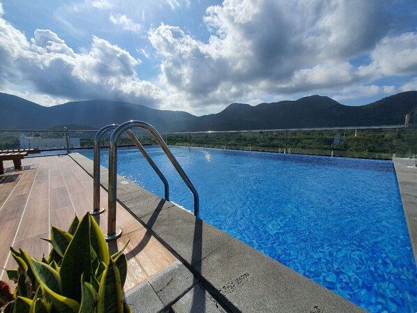 A swimming pool with a view of mountains and a cloudy sky.