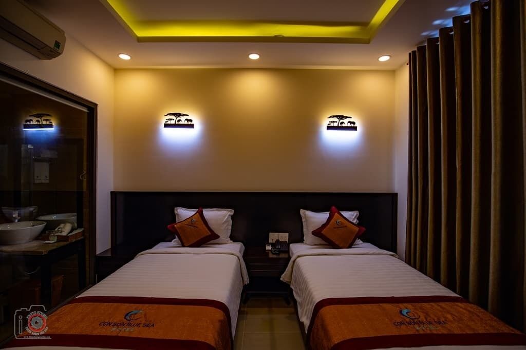 Une chambre d’hôtel avec deux lits, une table de chevet et une salle de bain visible.