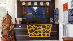 A hotel reception desk with clocks, a large sign for Con Son Blue Sea Hotel, and a decorative wooden sculpture. - Con Son Blue Sea (Ho Chi Minh City)