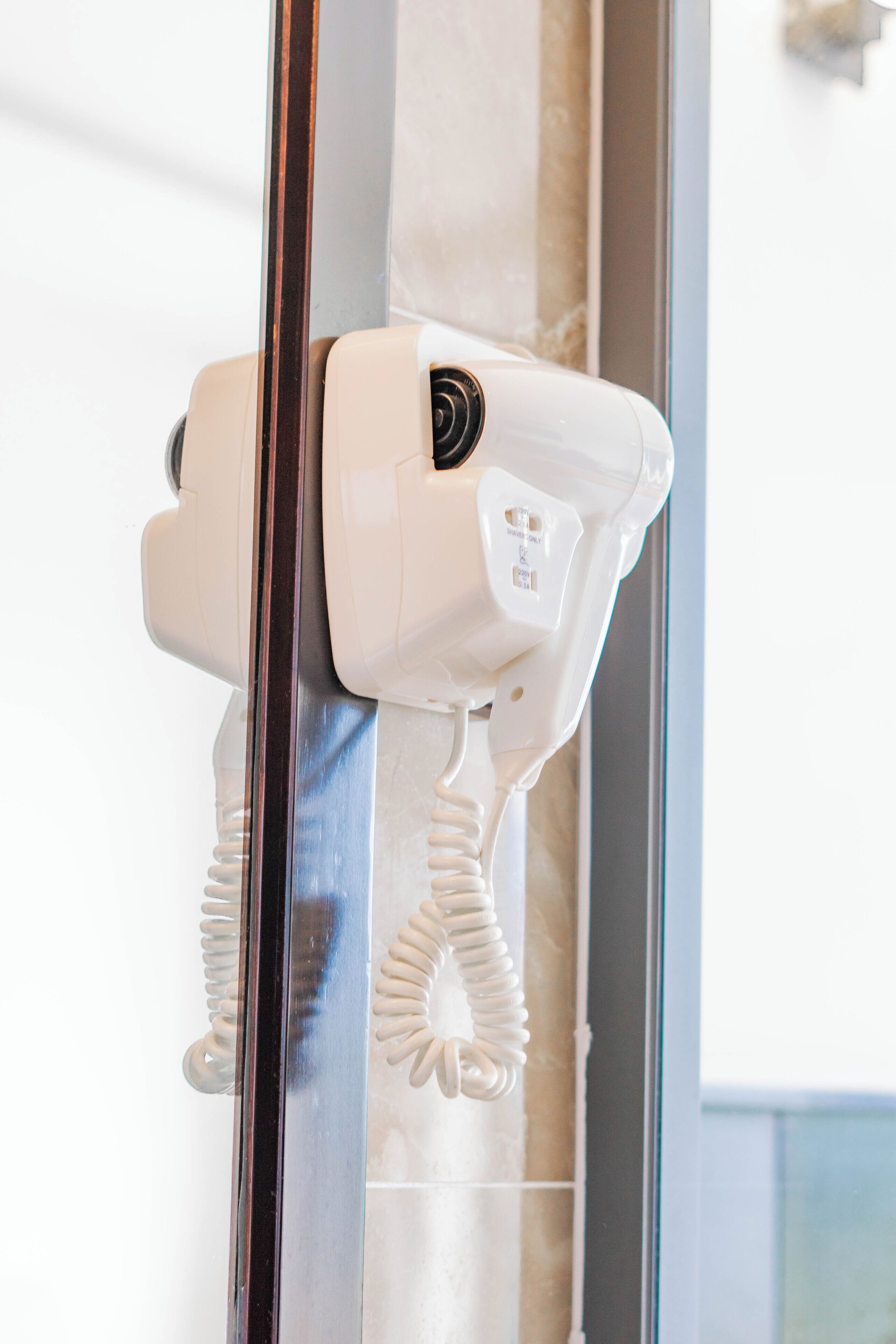 A hair dryer mounted on a glass shower door.