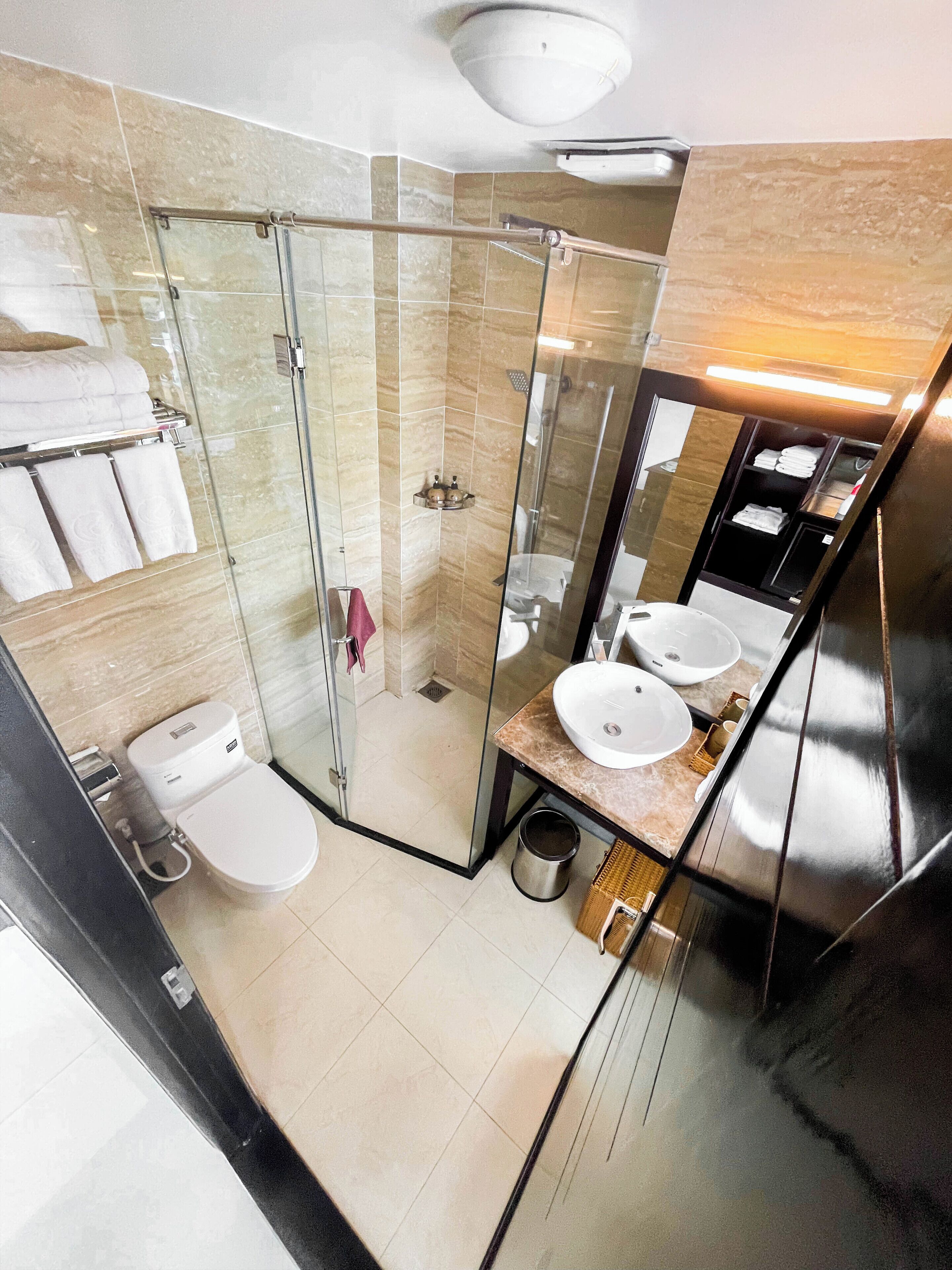 A modern bathroom with a glass shower enclosure, a toilet, and a vanity with two sinks.