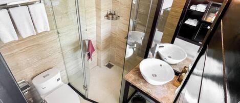 Un baño moderno con cabina de ducha de vidrio, inodoro y tocador con dos lavamanos.