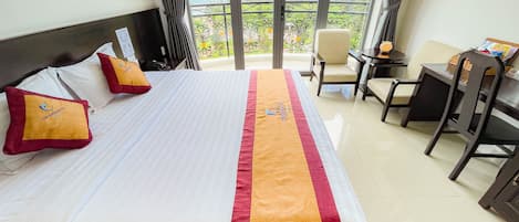 A hotel room with a large bed, two pillows, a desk, and a chair.