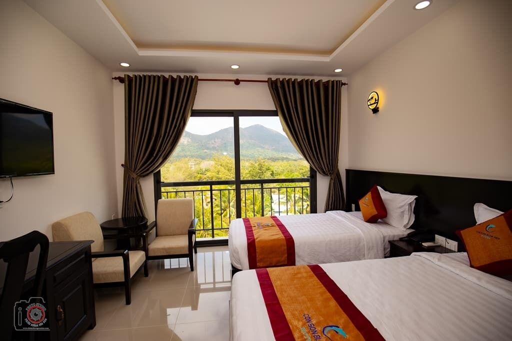 A hotel room with two beds, a TV, a desk, and a chair.