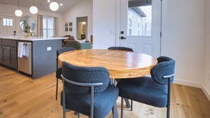 A modern kitchen with a central island, pendant lighting, and a dining area with a round table and chairs.
