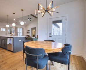 Uma cozinha moderna com ilha central, iluminação pendente e área de jantar com mesa redonda e cadeiras.