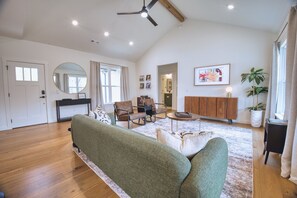 A spacious living room with a green sofa, a round coffee table, and a wooden cabinet.