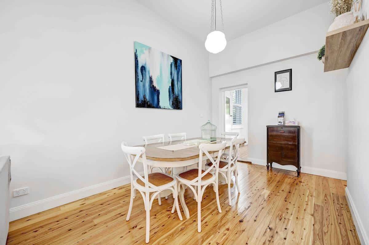 A dining area with a round table, white chairs, and a wooden floor.