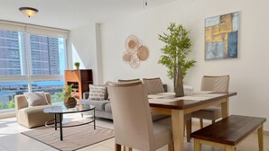 A modern living room with a dining area, large windows, and a city view. - Alojamiento con Vistas Costa del Este 1 (Panamá)