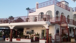 A multi-story building with balconies, a staircase, and potted plants.