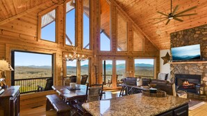 Un intérieur spacieux, avec des éléments en bois, une grande cheminée en pierre, un mur en pierre et un téléviseur fixé au-dessus.