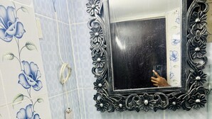 A bathroom with a white sink, a mirror with an ornate frame, and floral-patterned tiles. - Beautiful 1-Bed Studio in Dhaka (Dhaka)