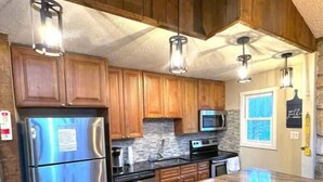 A kitchen with wooden cabinets, stainless steel appliances, a granite countertop, and pendant lighting.