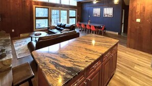 A spacious living area with a large island counter, a dining table with chairs, a sofa, and a fireplace.