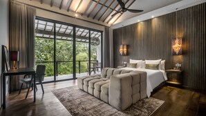 A modern bedroom with a large bed, a seating area, a desk, and a balcony with a view of greenery. - Umayam Luxury Townhouse 7 by Alfred in Bali (Canggu)