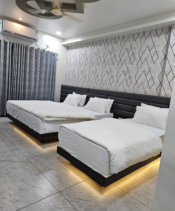 Quarto moderno com duas camas, parede cinza estampada e ventoinha no teto.