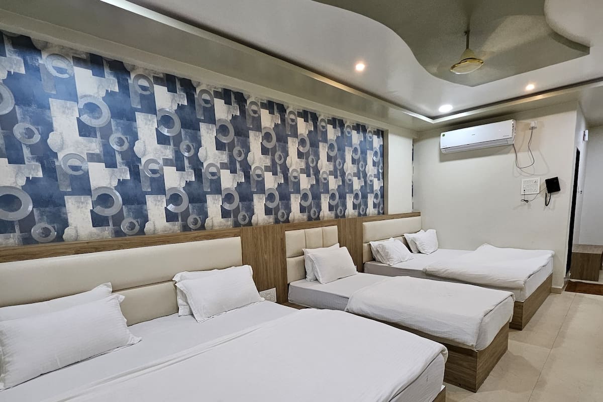 Habitación de hotel con cuatro camas, un diseño moderno de techo y una pared con estampado.
