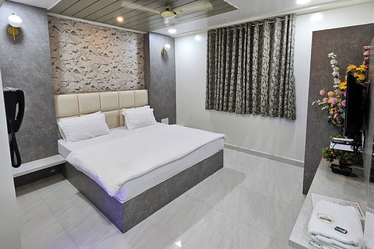 Un dormitorio moderno con una cama grande, un banco empotrado, un tocador con espejo y un panel decorativo en la pared.