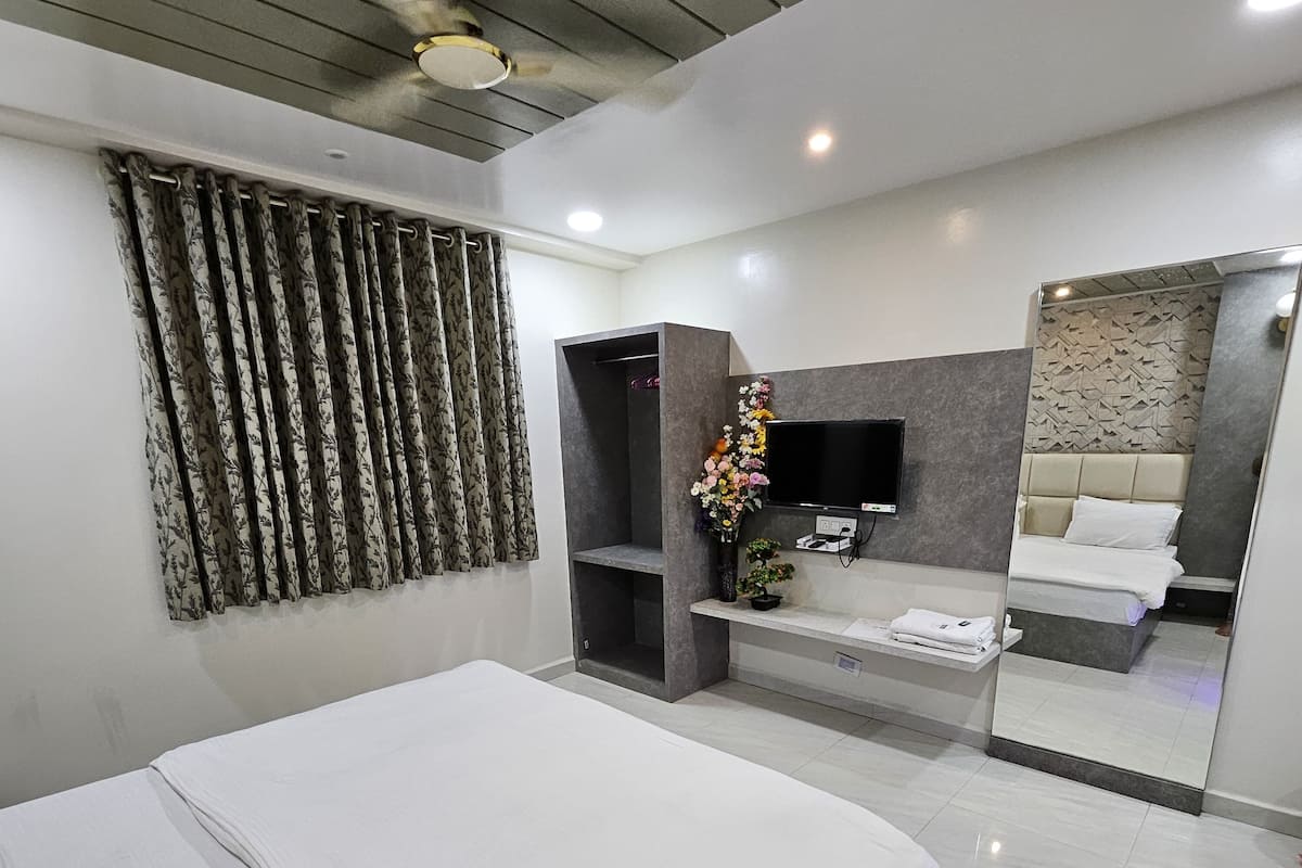 Un dormitorio moderno con una cama grande, un televisor empotrado, un tocador con espejo y una zona de ducha.