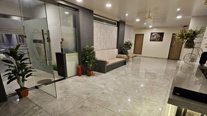 A spacious lobby with a marble floor, a reception desk, and potted plants. - Annapurna Executive (Tuljapur)