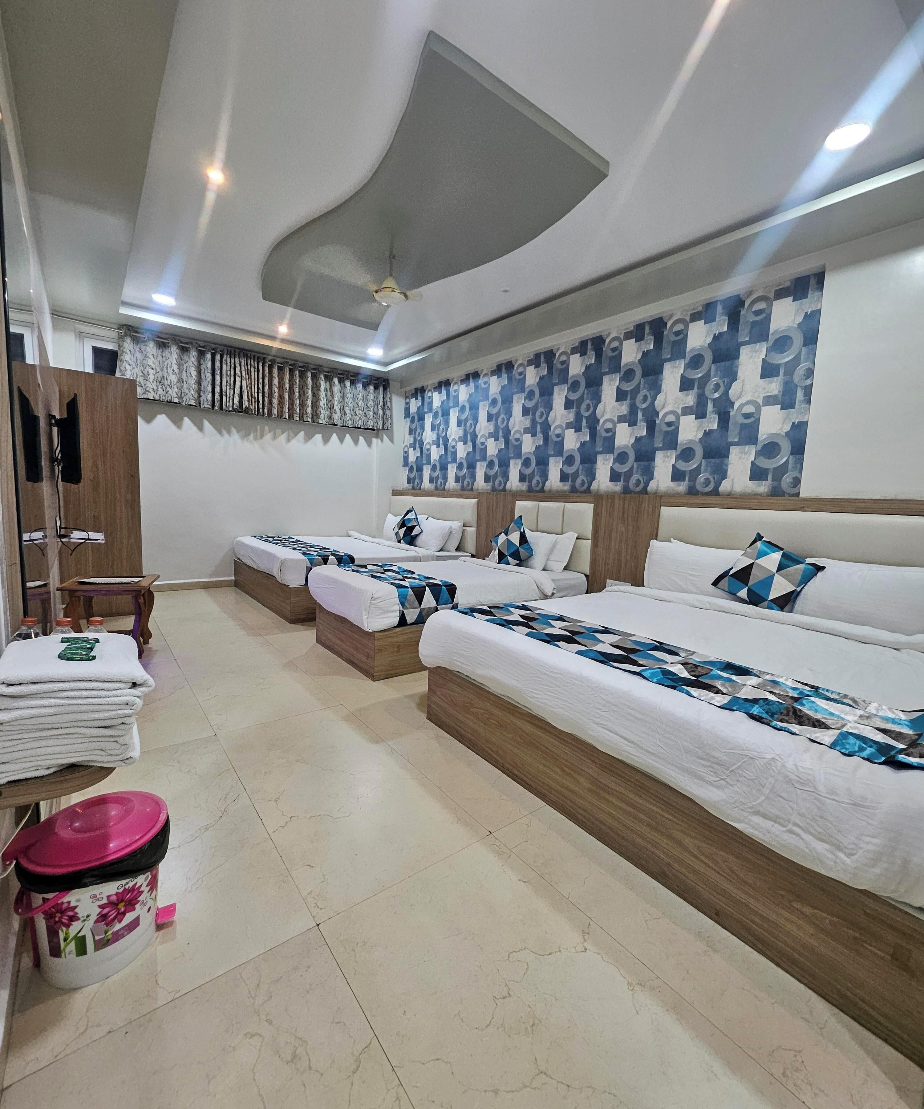 Habitación de hotel con dos camas, un armario de madera, una mesita con toallas y un adorno en la pared.