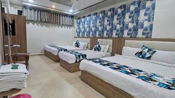 Habitación de hotel con dos camas, un armario de madera, una mesita con toallas y un adorno en la pared.