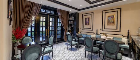 A hotel lobby with a patterned floor, seating area, and a large window with curtains.