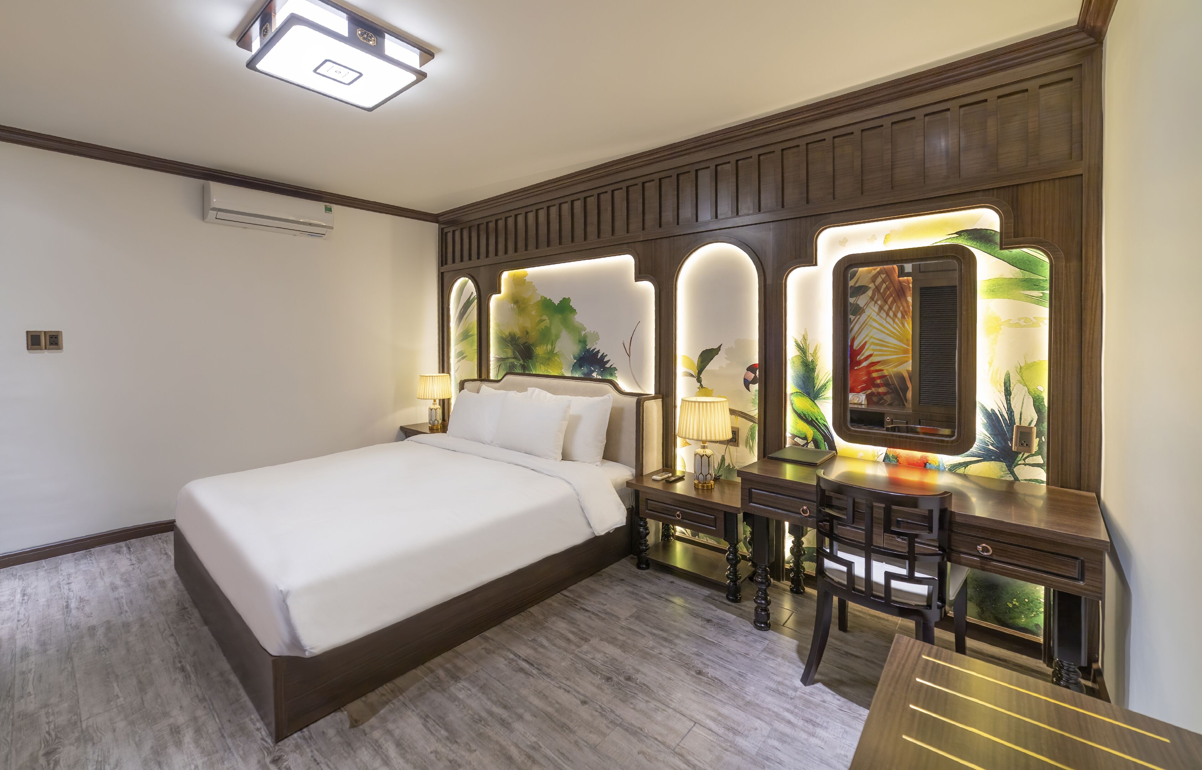 A hotel room with a large bed, a desk with a chair, and a vanity with a mirror.