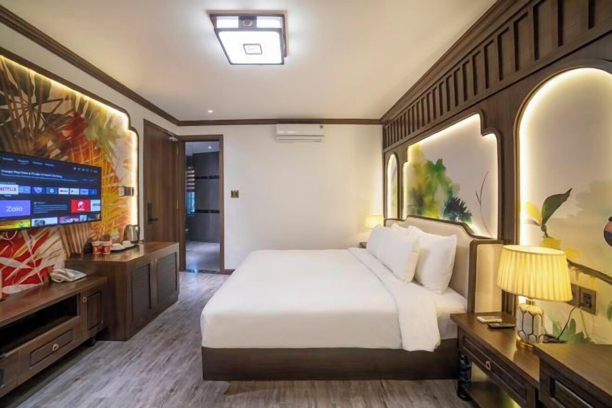 Habitación de hotel con una cama grande, televisión, escritorio y una obra de arte colgada en la pared.