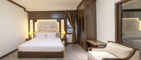 Une chambre d’hôtel avec un grand lit, un canapé, une table de chevet avec des lampes, une armoire et une grande fenêtre avec des rideaux.